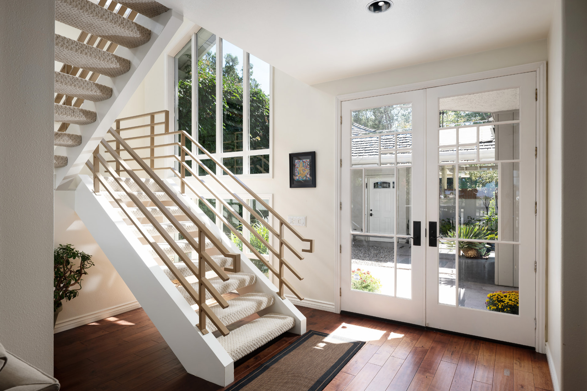 Sunlit entry foyer with open staircase and glass double doors