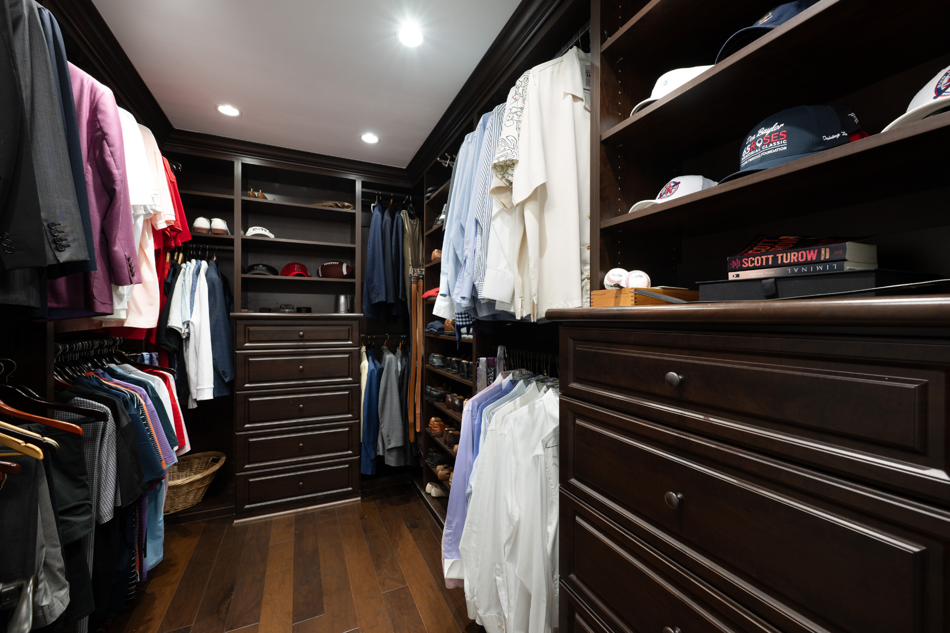 Walk-in closet with dark wood built-ins, drawers, and shelving