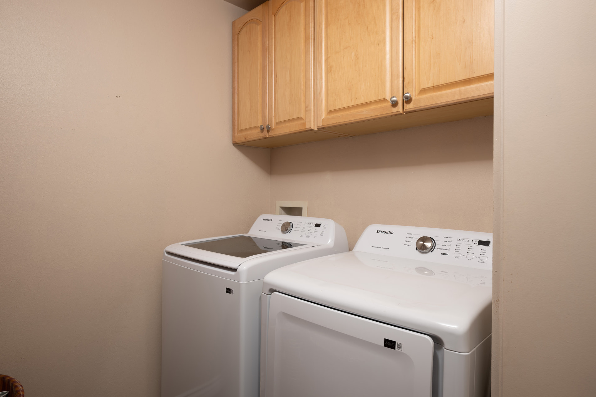 Laundry room with washer and dryer under maple cabinetry
