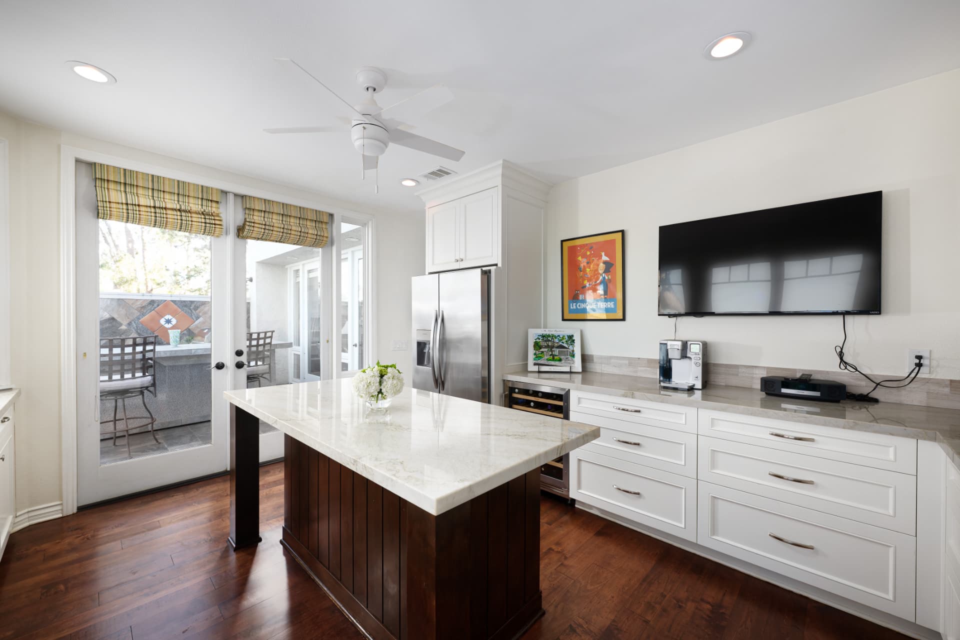 Kitchen island with marble counters, wine fridge, and French doors to the patio