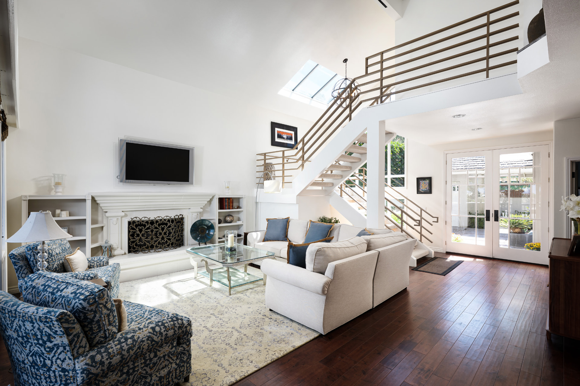 Living room with staircase, skylight, and French doors to the patio