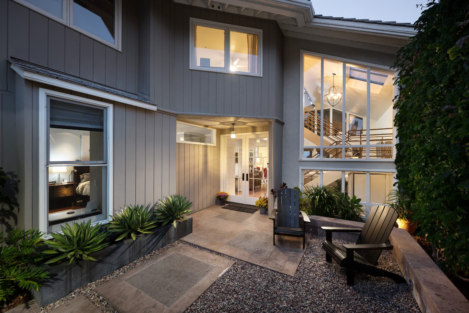 Twilight view of the lighted entry courtyard and front patio of 36 Vienna